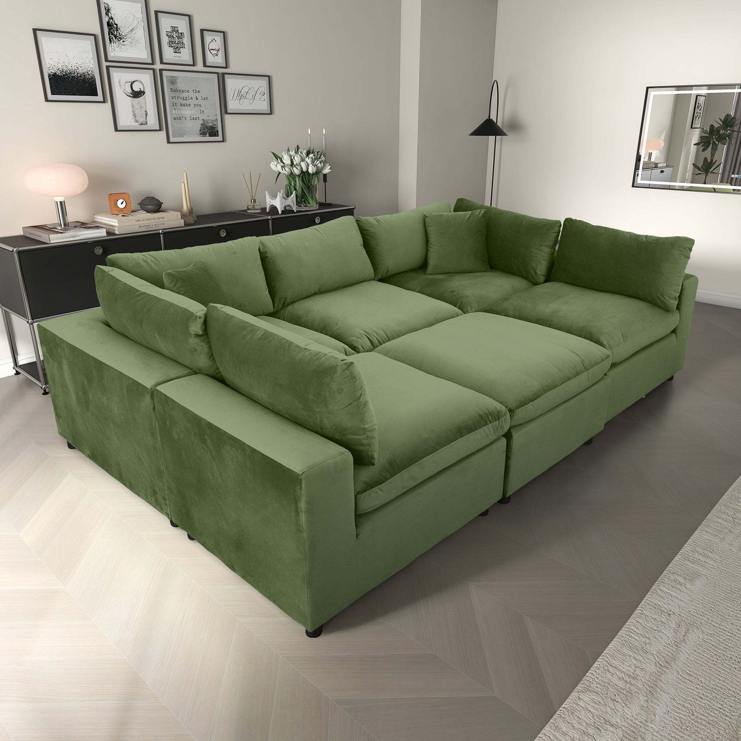 Modern living room with large green sectional sofa, wall art, and black console table