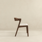 Modern wooden dining chair with white cushion, side view, on neutral background