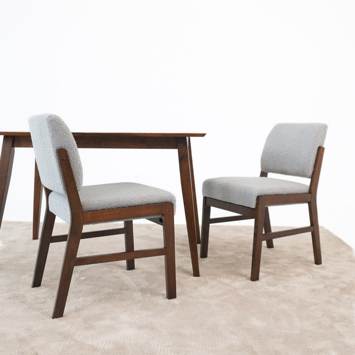 Modern wood dining table with two gray upholstered chairs on beige rug