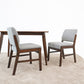Modern wood dining table with two gray upholstered chairs on beige rug