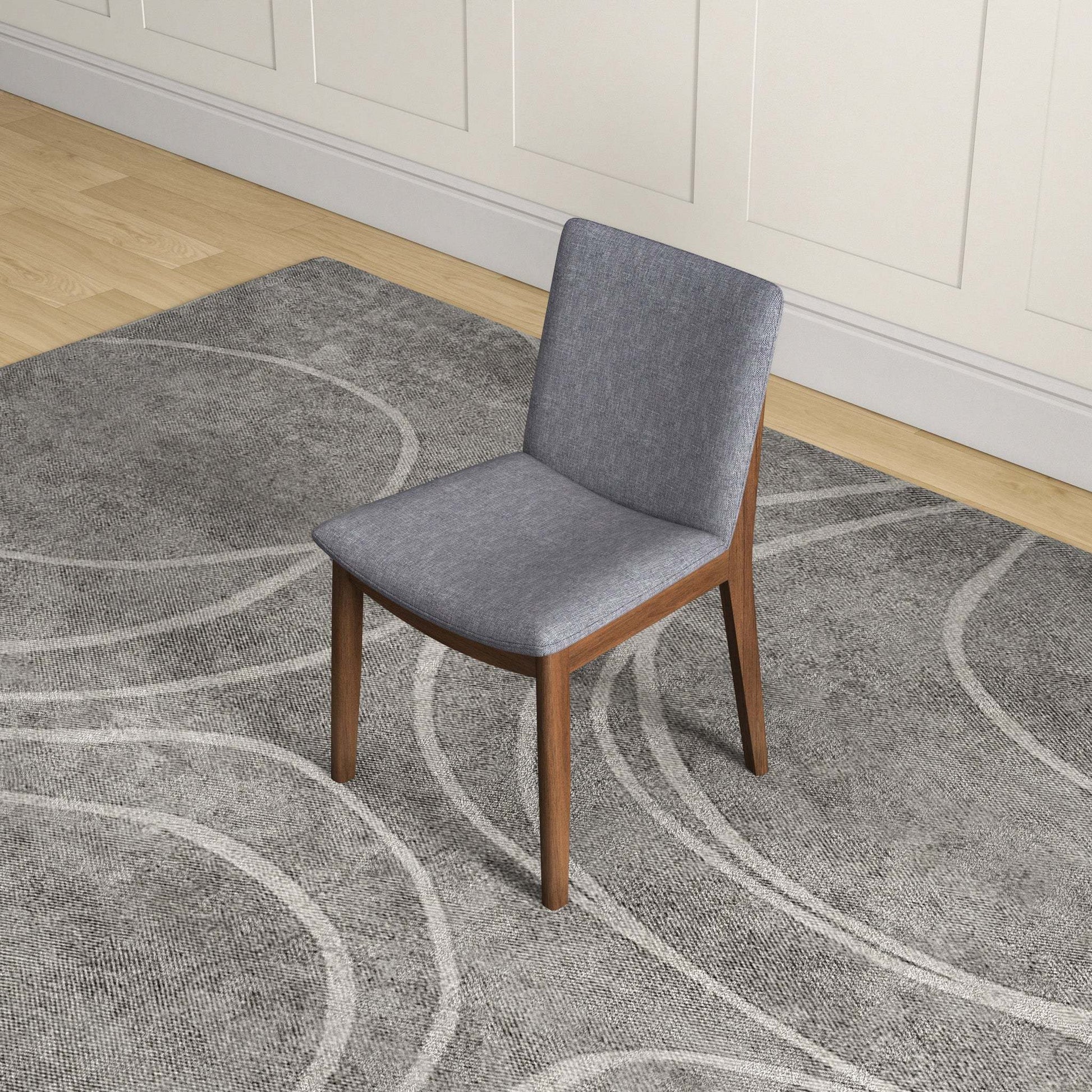 Modern gray upholstered chair with wooden legs on patterned rug in home interior