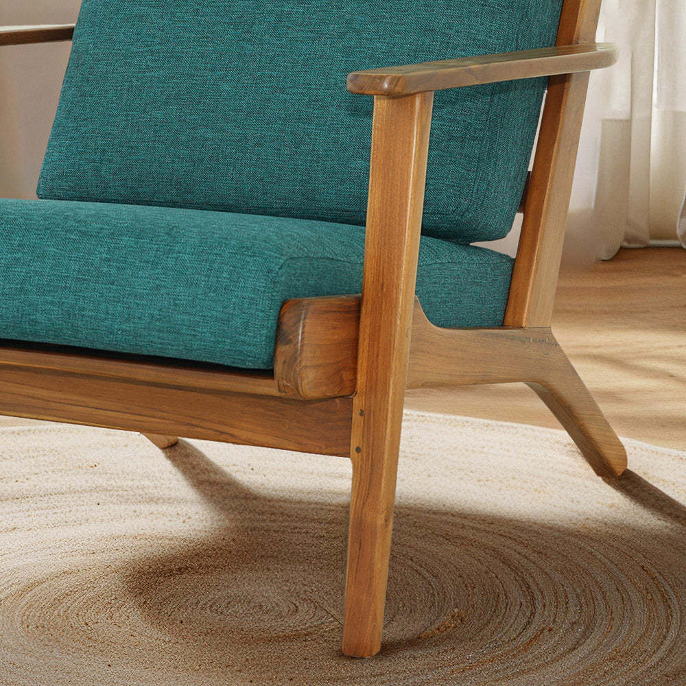 Mid-century modern wooden armchair with teal cushions on beige carpet, FredCo International furniture