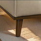 Modern beige leather sofa corner with wooden leg on light speckled flooring