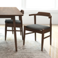 Mid-century modern wood dining chair with dark cushion next to matching table in bright room