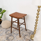 Woven leather seat wooden barstool on a patterned rug with decor in a modern home setting