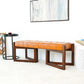 Modern caramel leather bench with wood legs in a stylish living room setting, FredCo International furniture