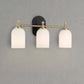 Modern three-light wall sconce with frosted glass shades and brass accents on gray wall