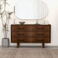 Modern wood dresser with six drawers, large mirror, and minimalist home decor in a bright room.