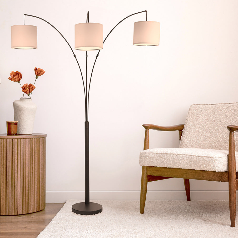 Modern living room with a three-light floor lamp, wood armchair, and side table decor