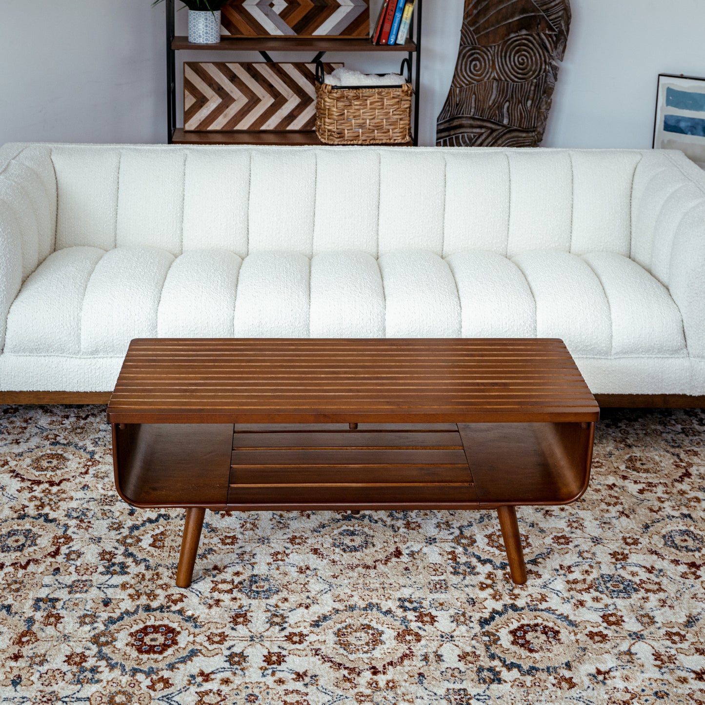 Mid-century modern wood coffee table in front of a white sofa on patterned rug, FredCo International