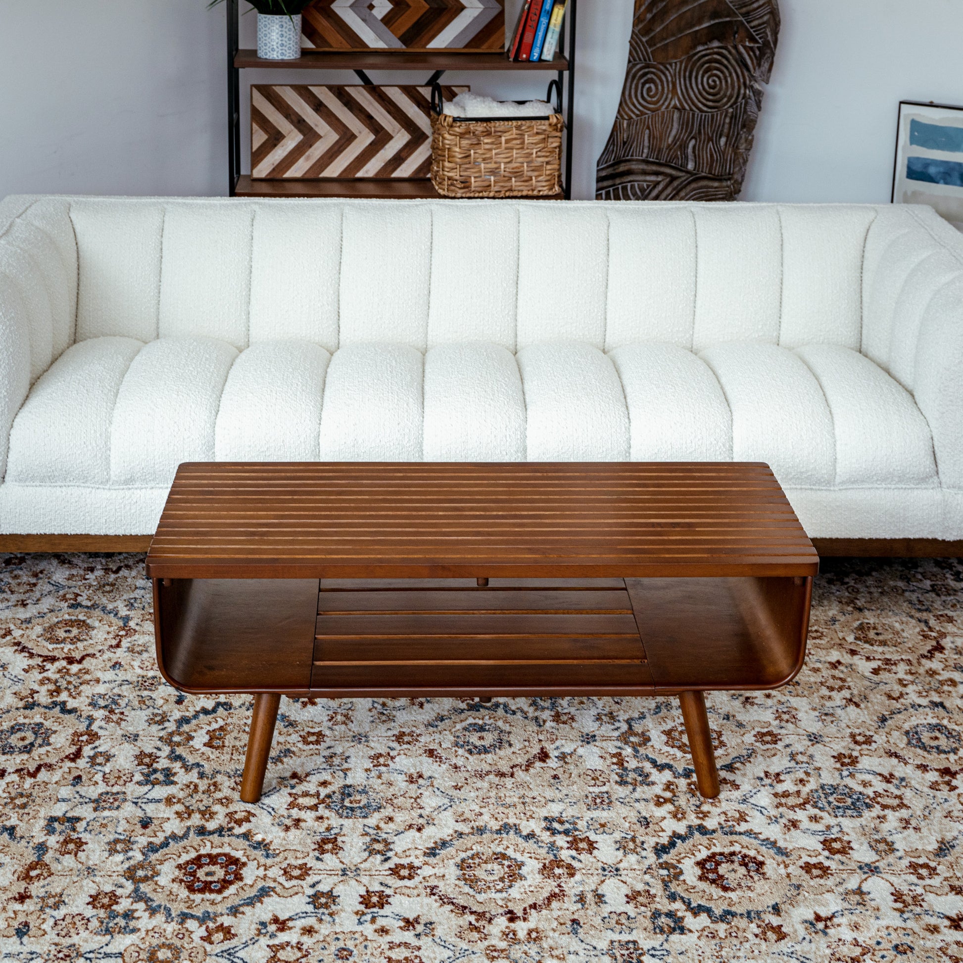 Mid-century modern wood coffee table in front of a white sofa on patterned rug, FredCo International
