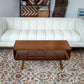 Mid-century modern wood coffee table in front of a white sofa on patterned rug, FredCo International