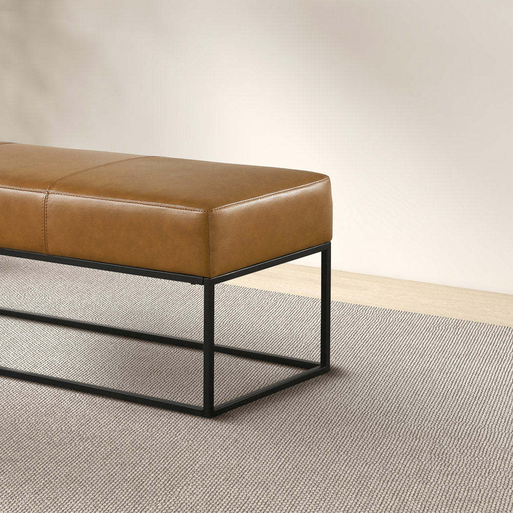 Modern brown leather bench with black metal frame on textured area rug, FredCo International furniture