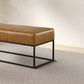 Modern brown leather bench with black metal frame on textured area rug, FredCo International furniture