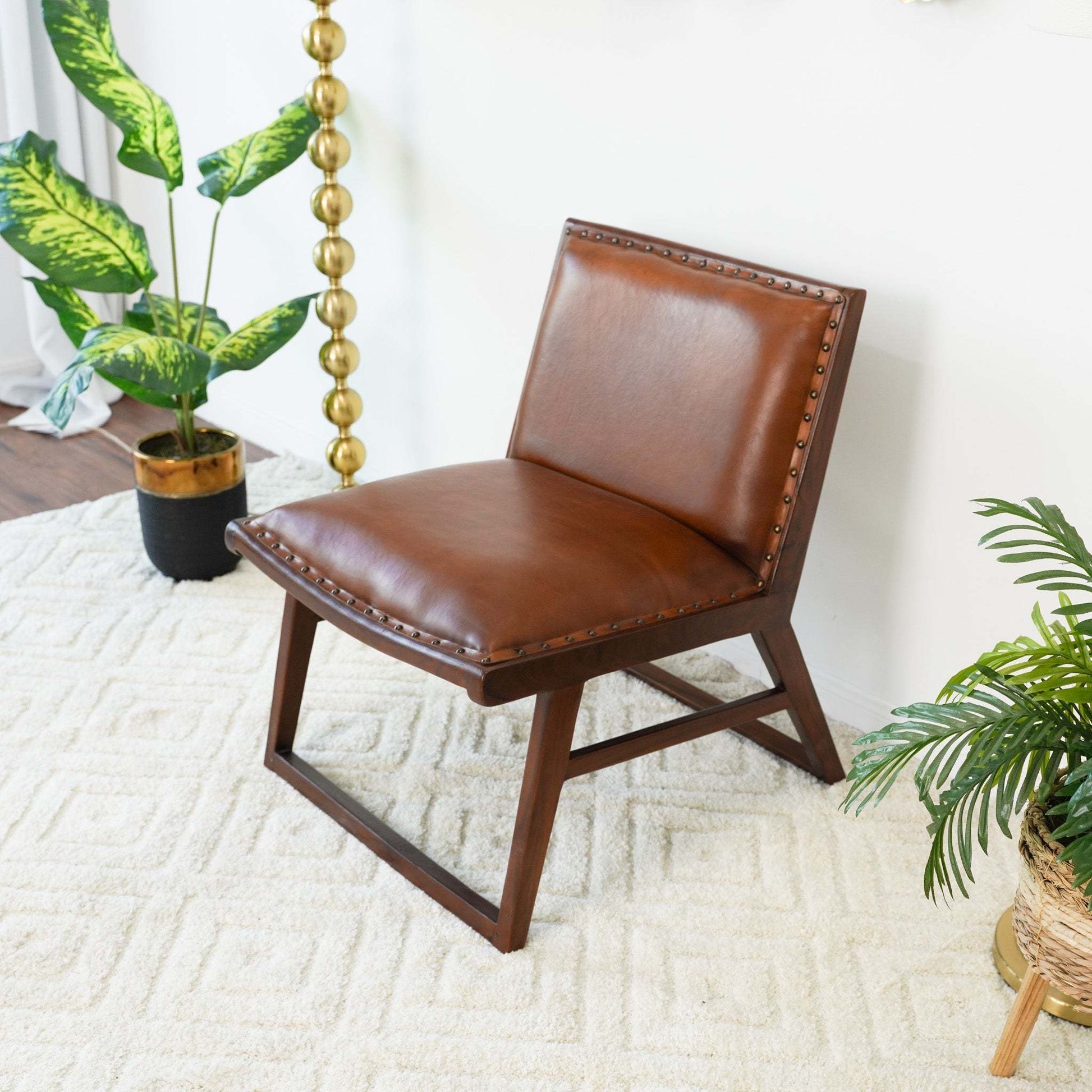 Modern brown leather accent chair on cream rug with indoor plants, FredCo International furniture