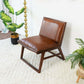 Modern brown leather accent chair on cream rug with indoor plants, FredCo International furniture