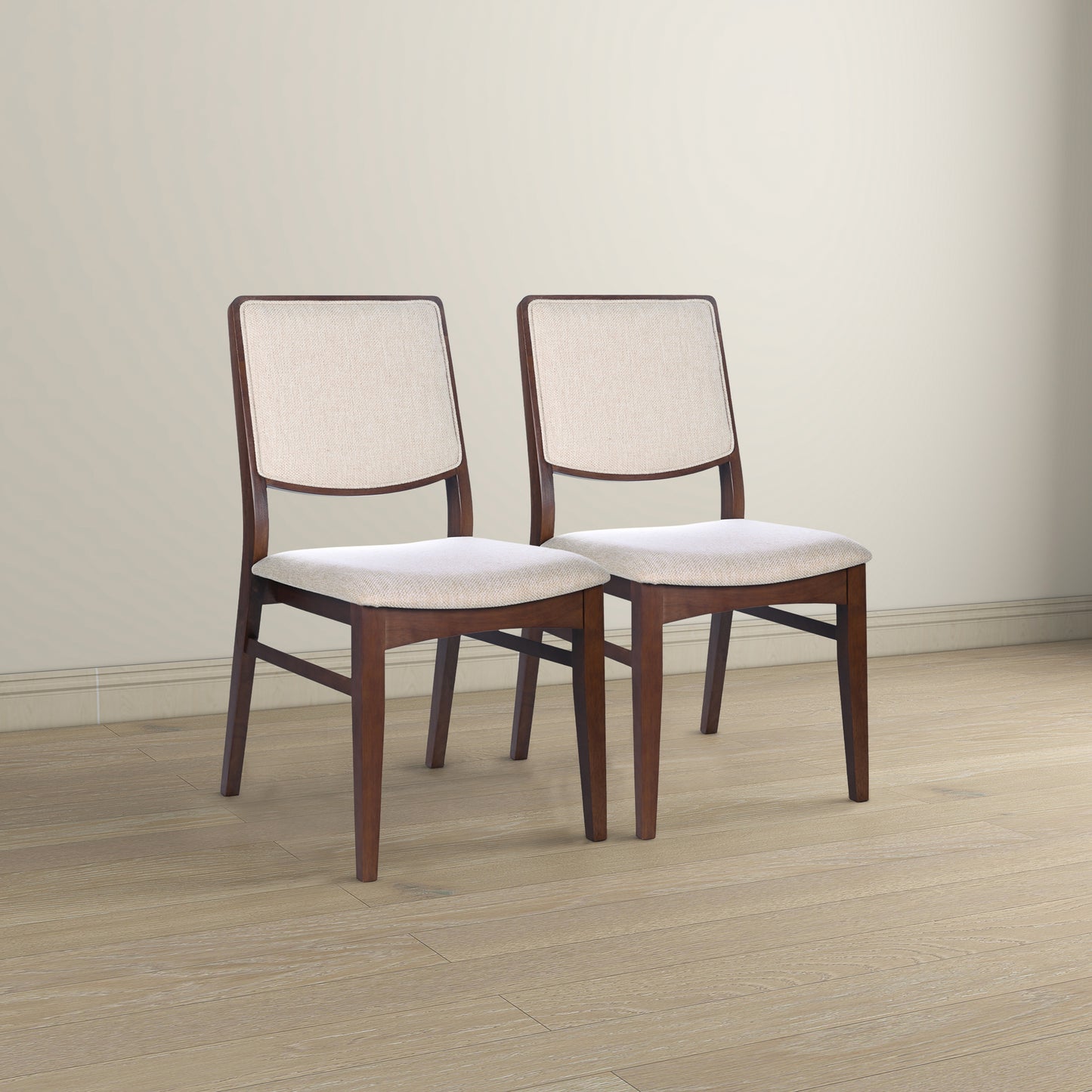 Pair of modern dining chairs with wooden frames and beige upholstery on hardwood floor