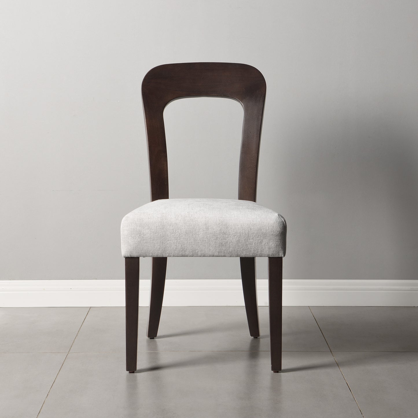 Modern dining chair with dark wood frame and light fabric seat in minimalist room from FredCo International