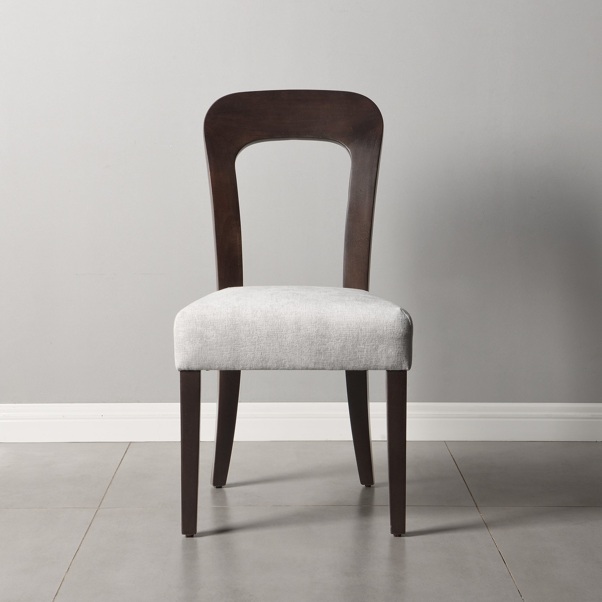 Modern dining chair with dark wood frame and light fabric seat in minimalist room from FredCo International