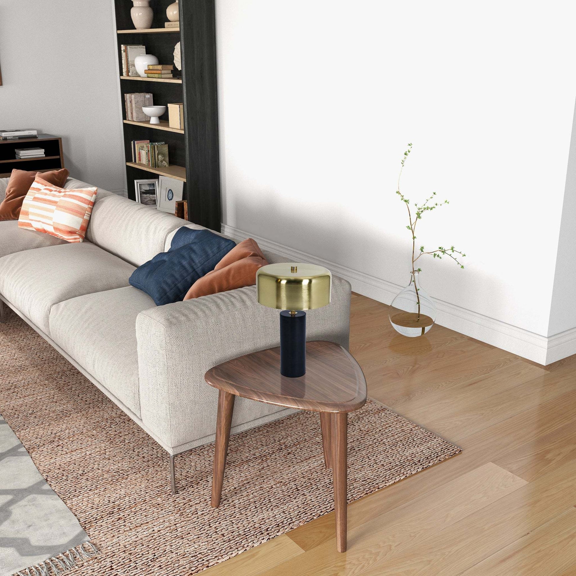 Modern living room with beige sofa, accent pillows, wood side table, and gold table lamp