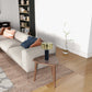 Modern living room with beige sofa, accent pillows, wood side table, and gold table lamp