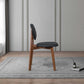 Modern wood chair with black cushion on rug in stylish living room, FredCo International furniture