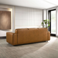 Modern brown leather sofa in bright living room with large window and plant, FredCo International