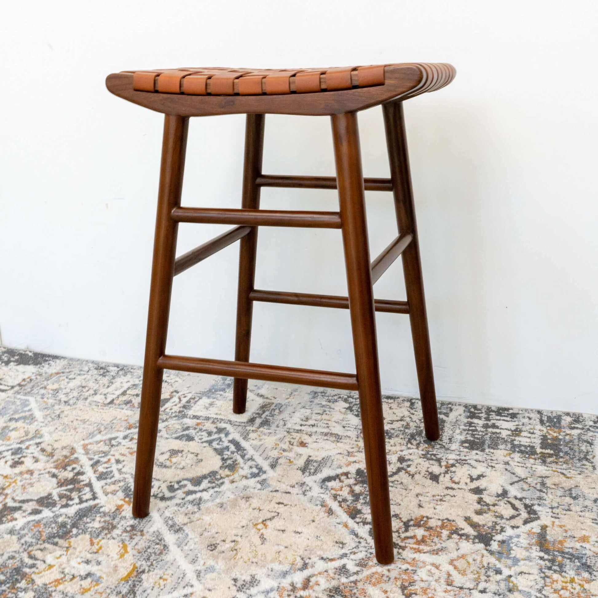 Wooden bar stool with woven leather seat on patterned rug, FredCo International furniture