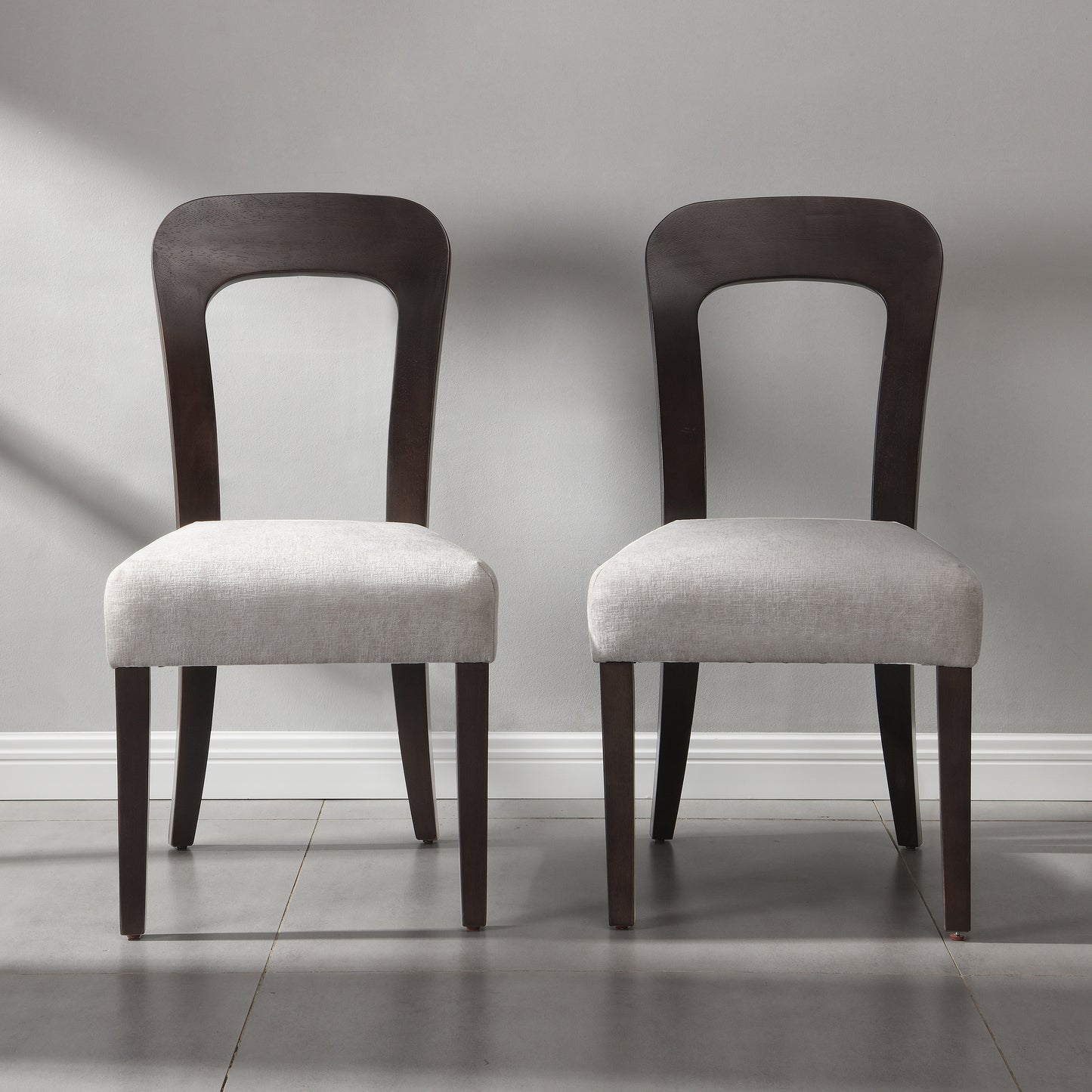 Pair of modern dining chairs with dark wood frames and light upholstered seats