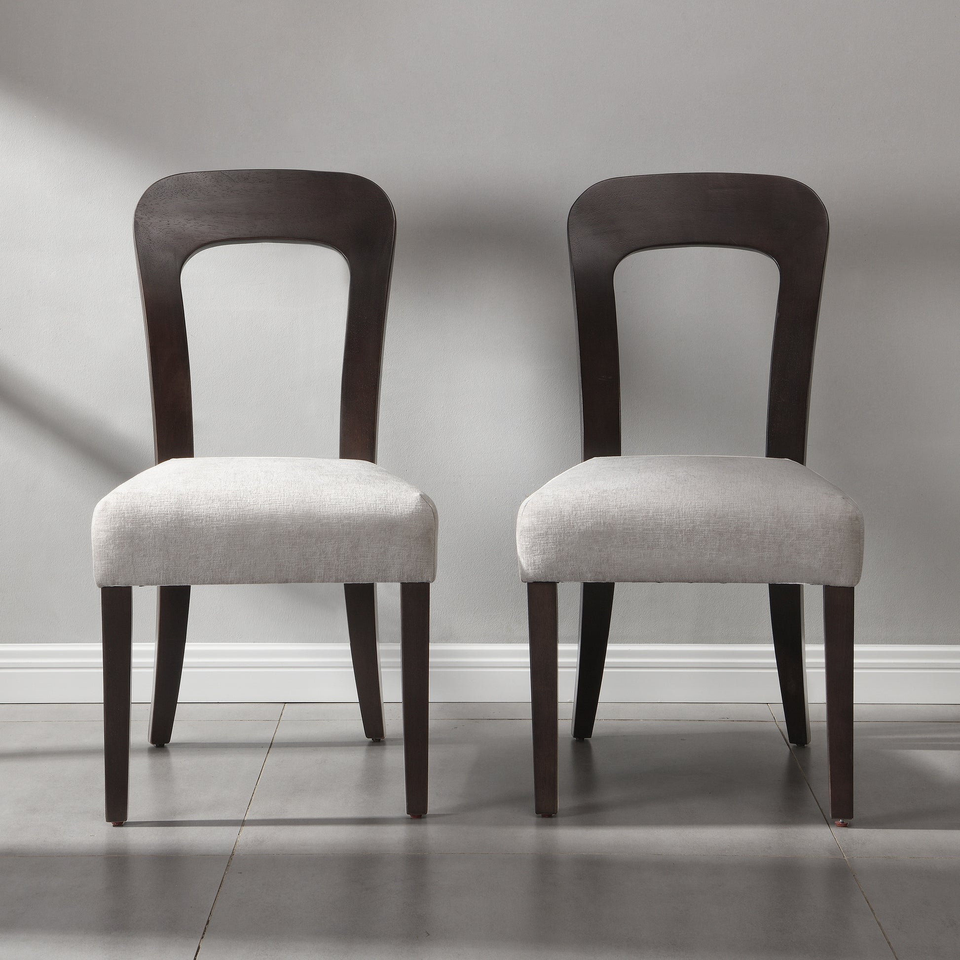Pair of modern dining chairs with dark wood frames and light upholstered seats