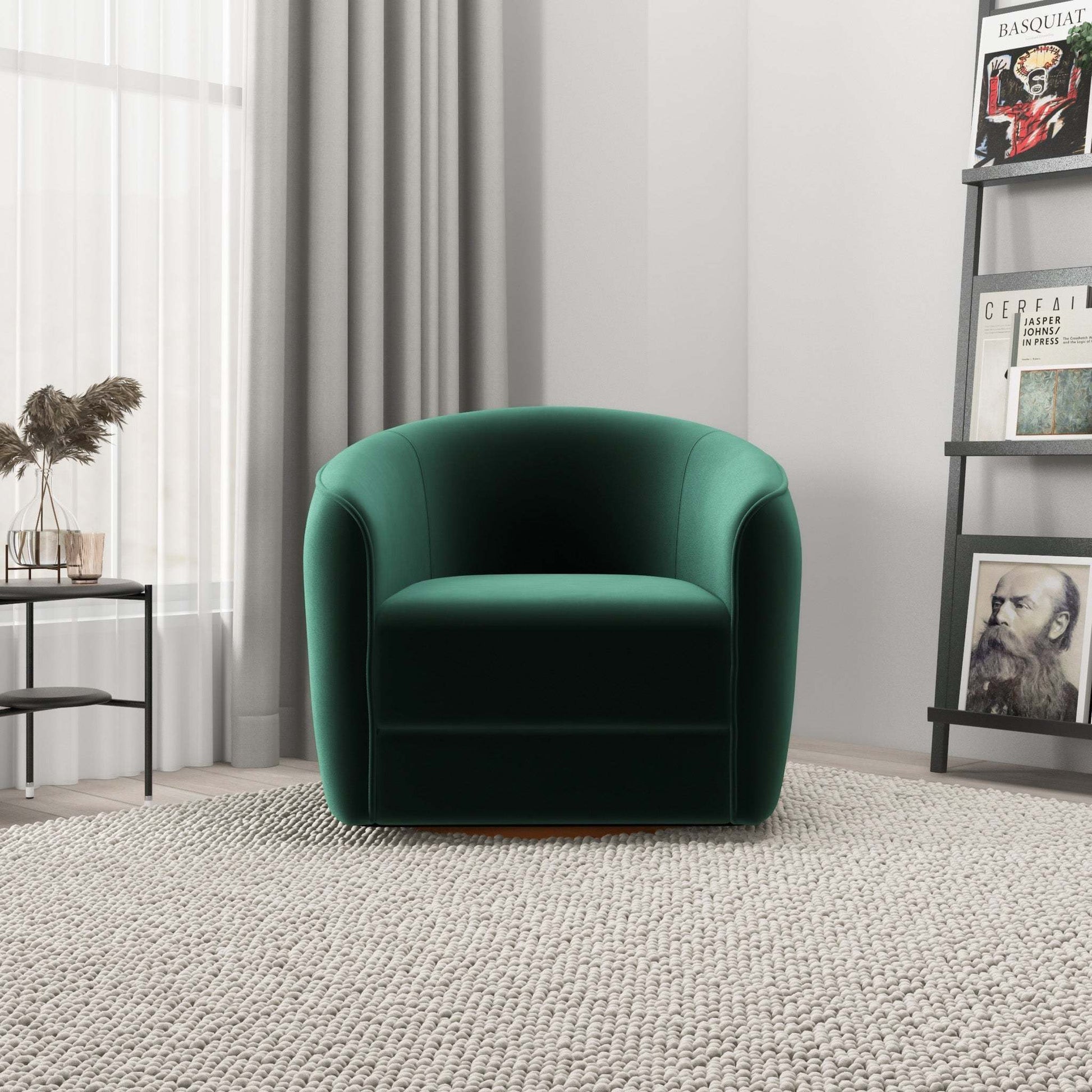 Modern green velvet armchair in a bright living room with a textured rug, bookshelf, and side table.