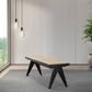 Modern woven bench with black legs on gray rug, pendant lights, and plant by window