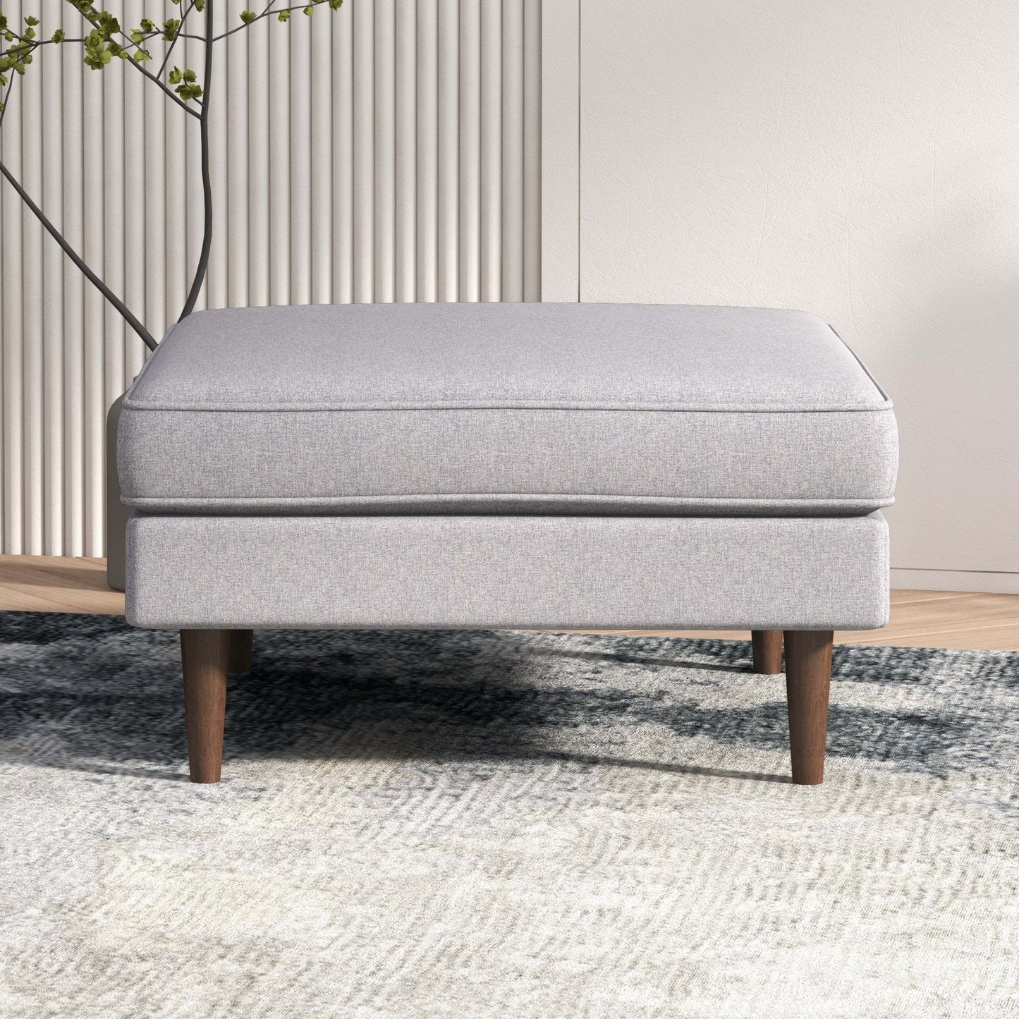 Modern light gray upholstered ottoman with wooden legs on a textured rug
