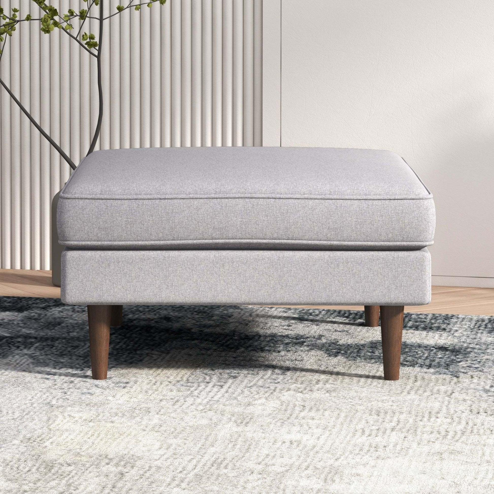 Modern light gray upholstered ottoman with wooden legs on a textured rug