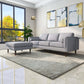 Modern living room with gray sofa and ottoman, large window, abstract wall art, and indoor plant
