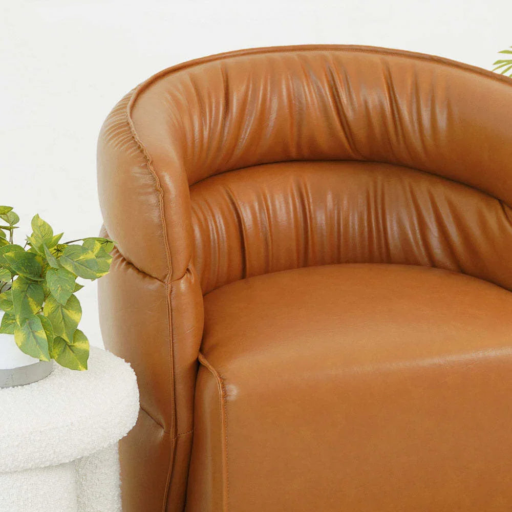 Modern brown leather accent chair with plush curved backrest beside white table and green plant