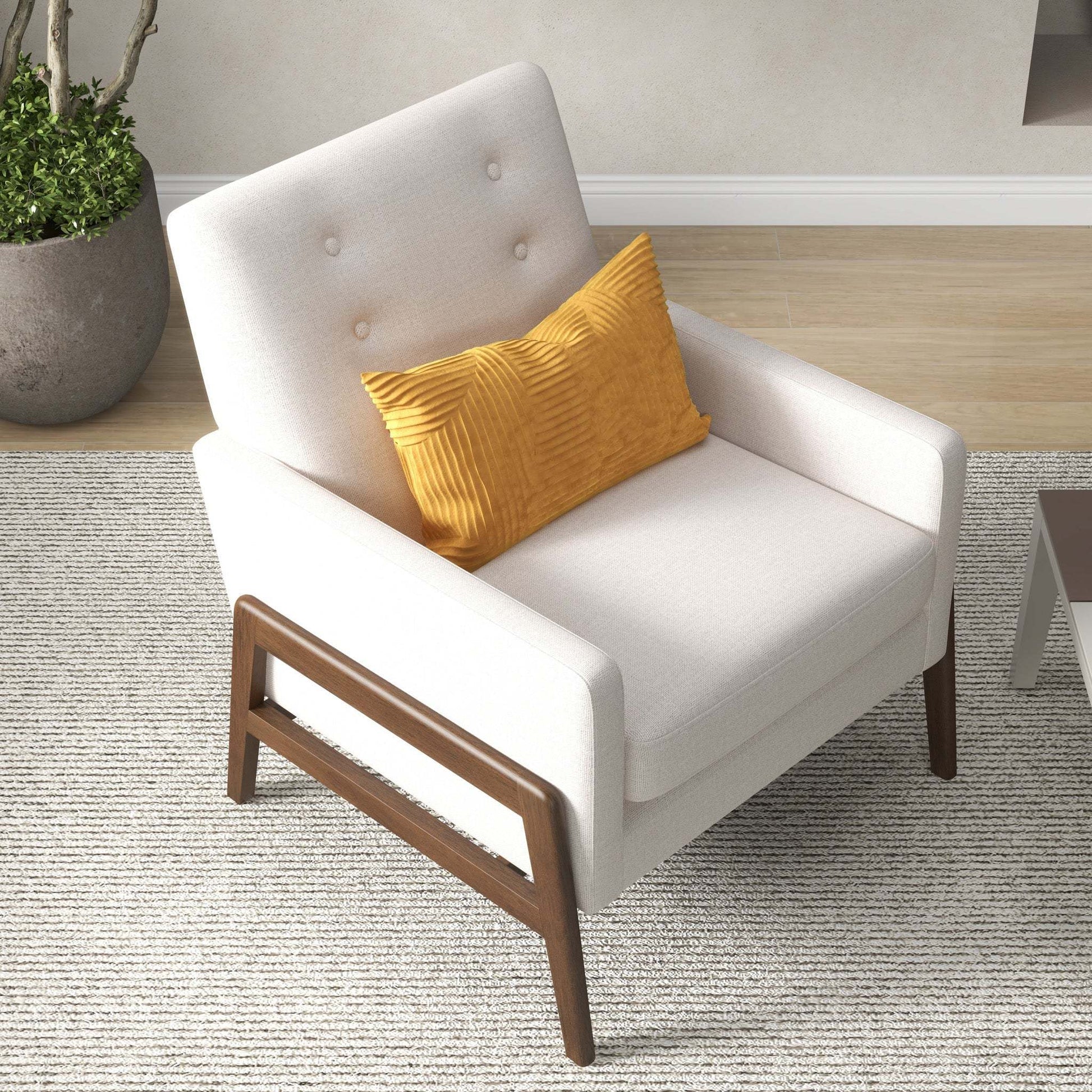 Modern beige armchair with wooden legs and yellow cushion on a textured rug, FredCo furniture
