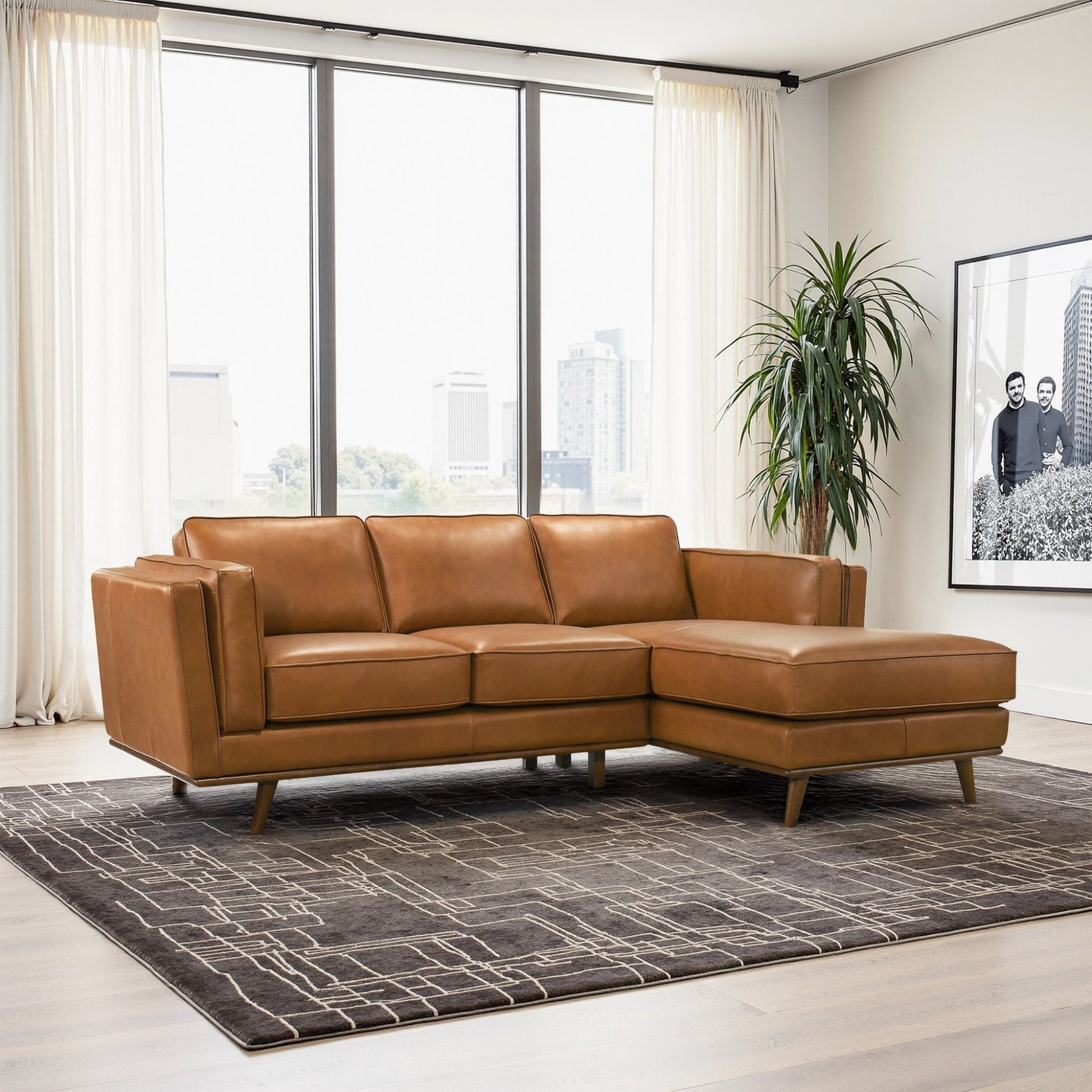 Modern tan leather sectional sofa in bright living room with large windows and geometric rug