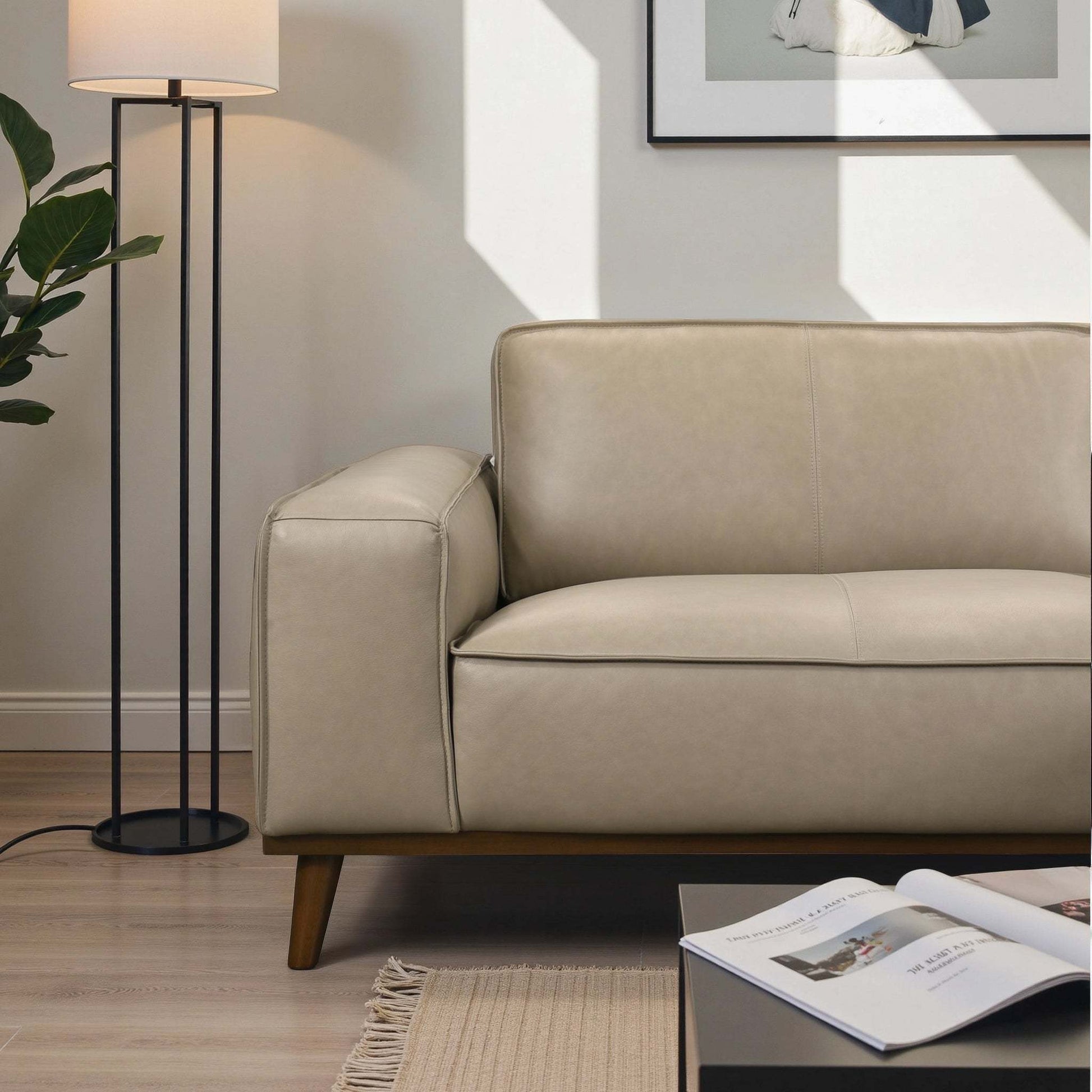 Modern beige leather sofa in a bright living room with floor lamp and coffee table