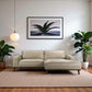 Modern beige sectional sofa in living room with houseplants, framed artwork, and pendant light
