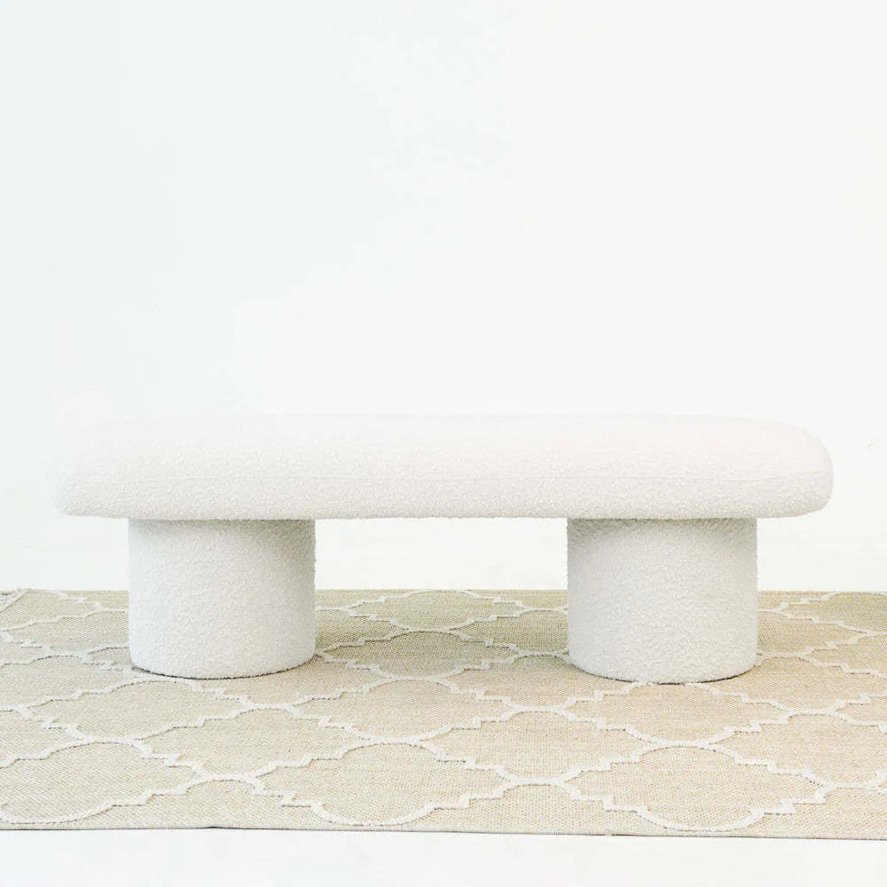 Modern white upholstered bench with rounded edges on beige patterned rug, home furniture