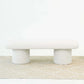 Modern white upholstered bench with rounded edges on beige patterned rug, home furniture