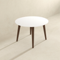 Modern round white dining table with wooden legs in minimalist room at FredCo International