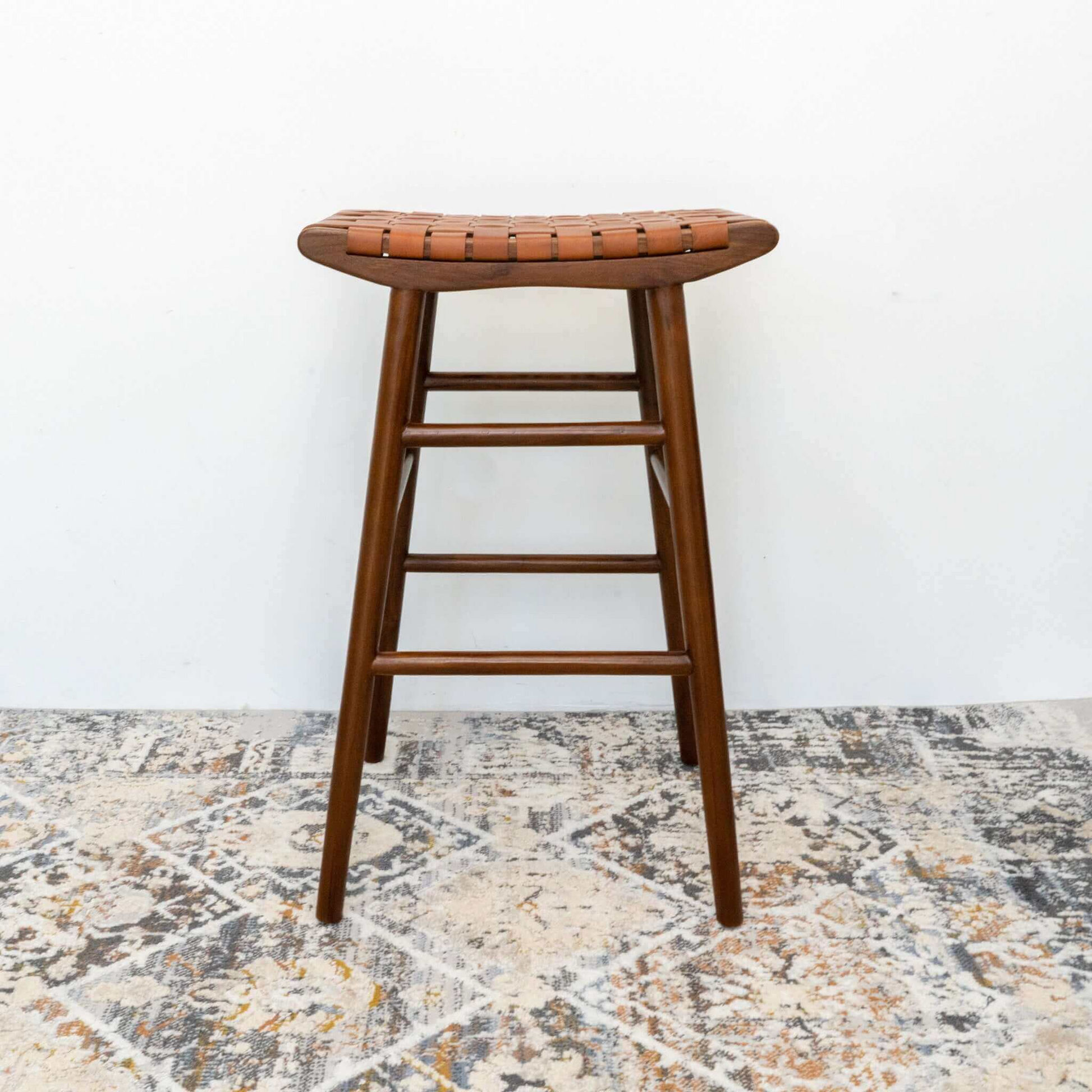 Modern wooden bar stool with woven leather seat on patterned rug, FredCo International furniture
