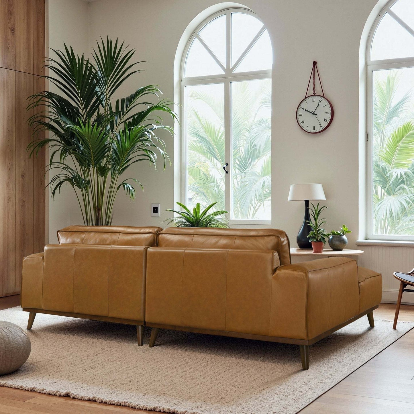 Modern living room with tan leather sofas, indoor plants, and arched windows at FredCo International