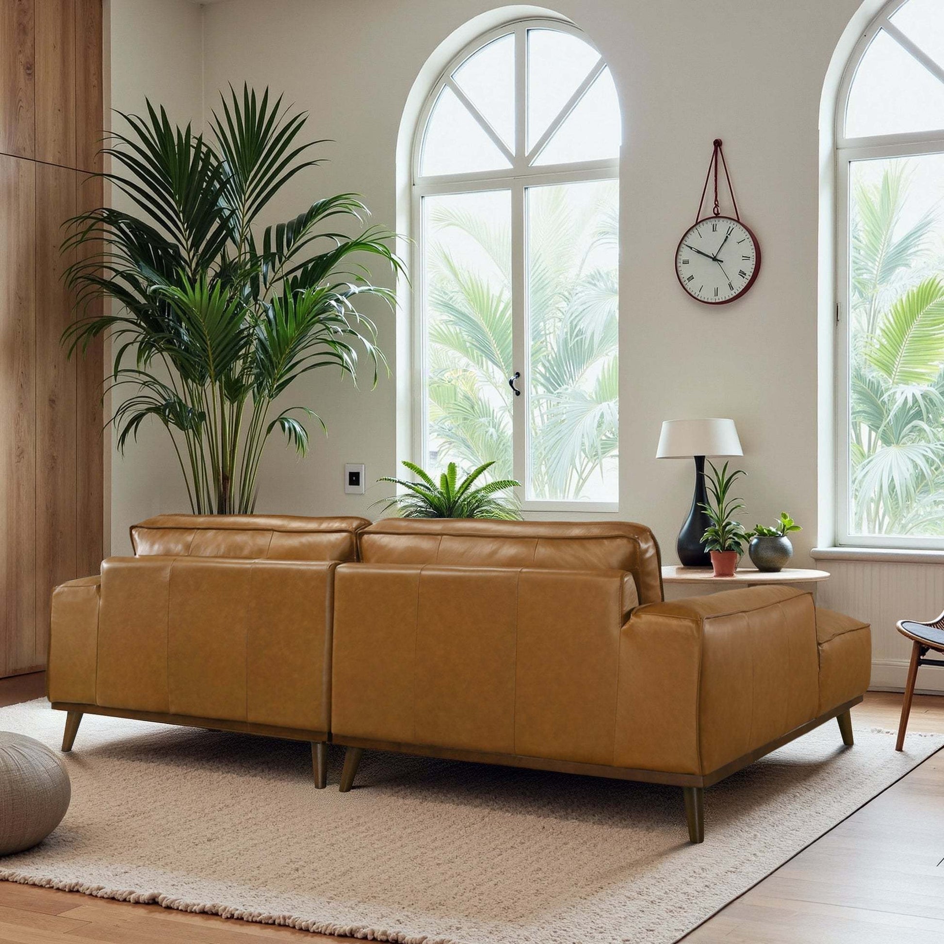 Modern living room with tan leather sofas, indoor plants, and arched windows at FredCo International