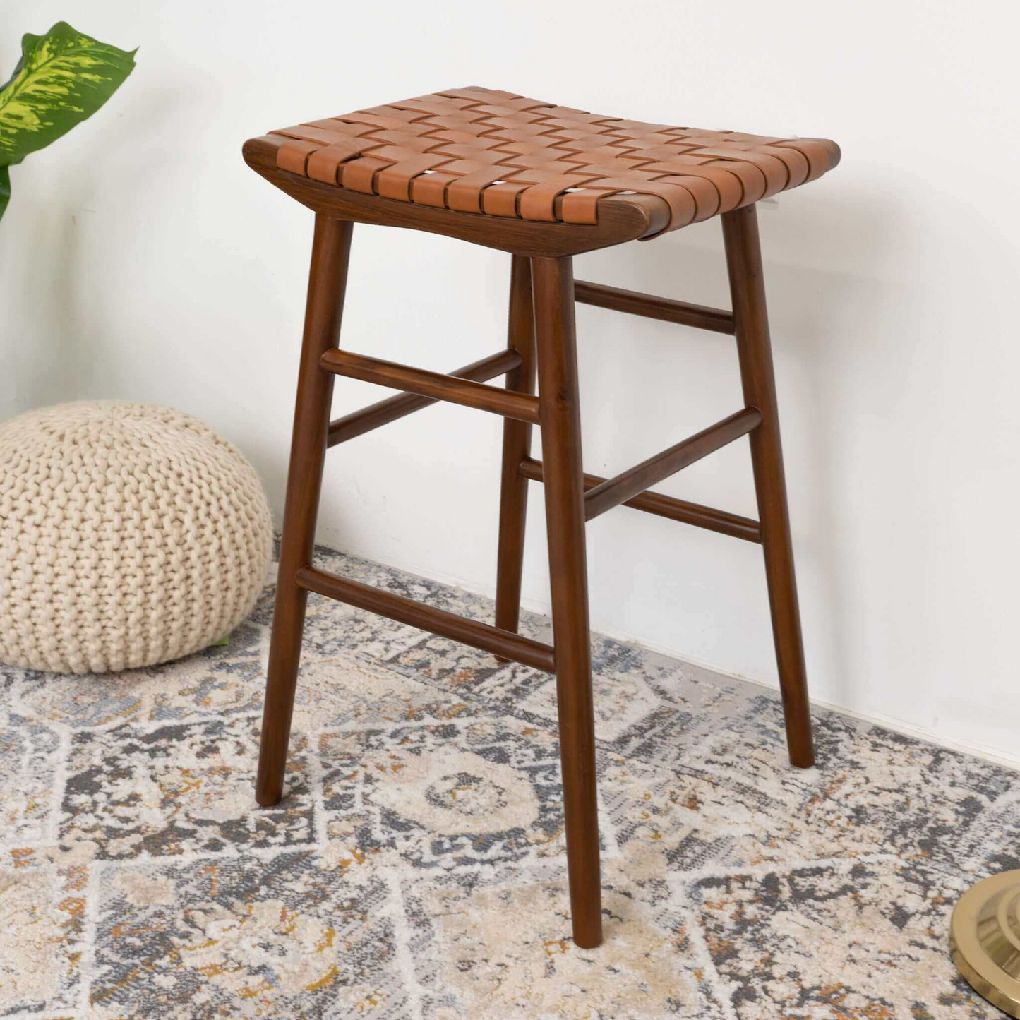 Modern wooden counter stool with woven leather seat on patterned rug, home furniture decor