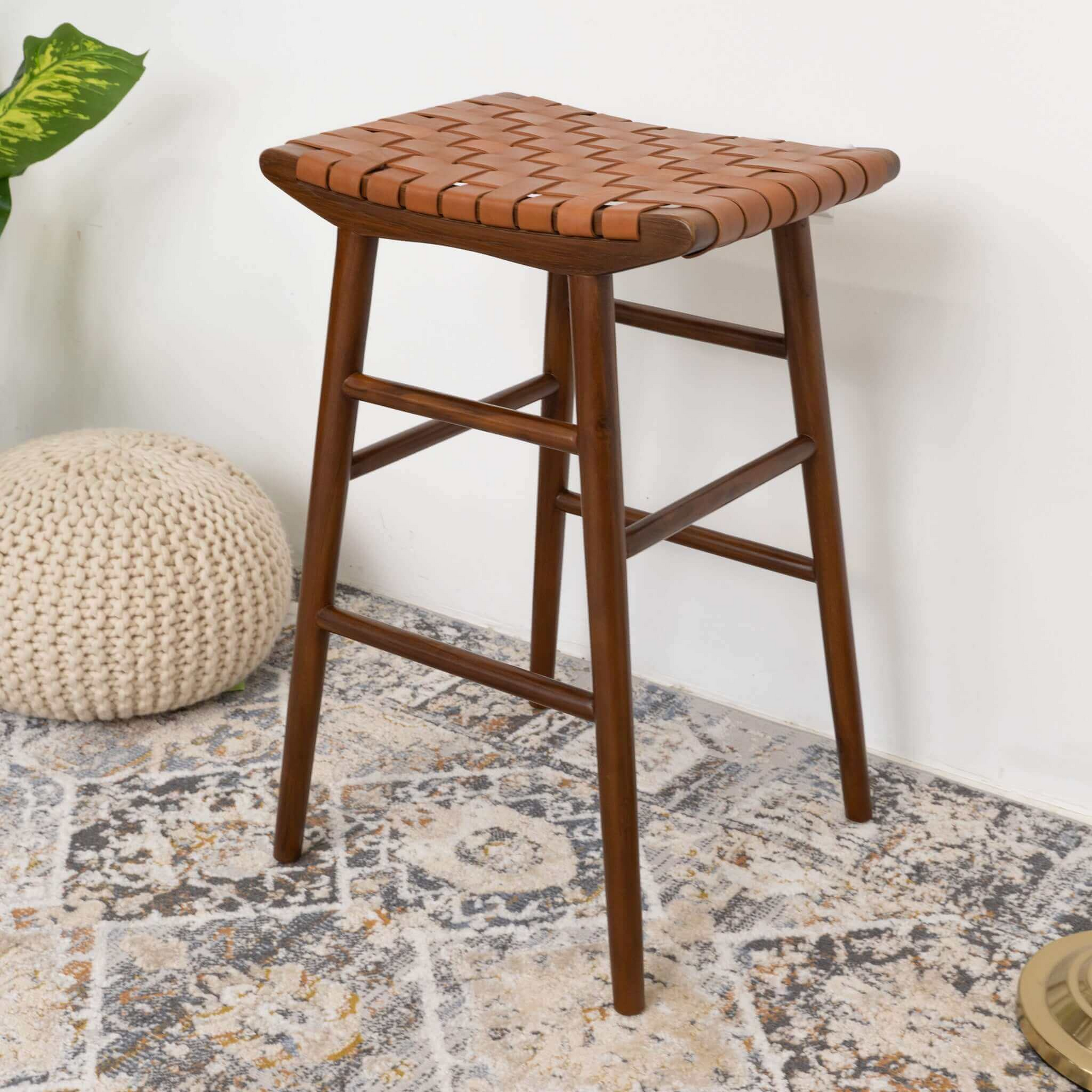 Modern wooden counter stool with woven leather seat on patterned rug, home furniture decor