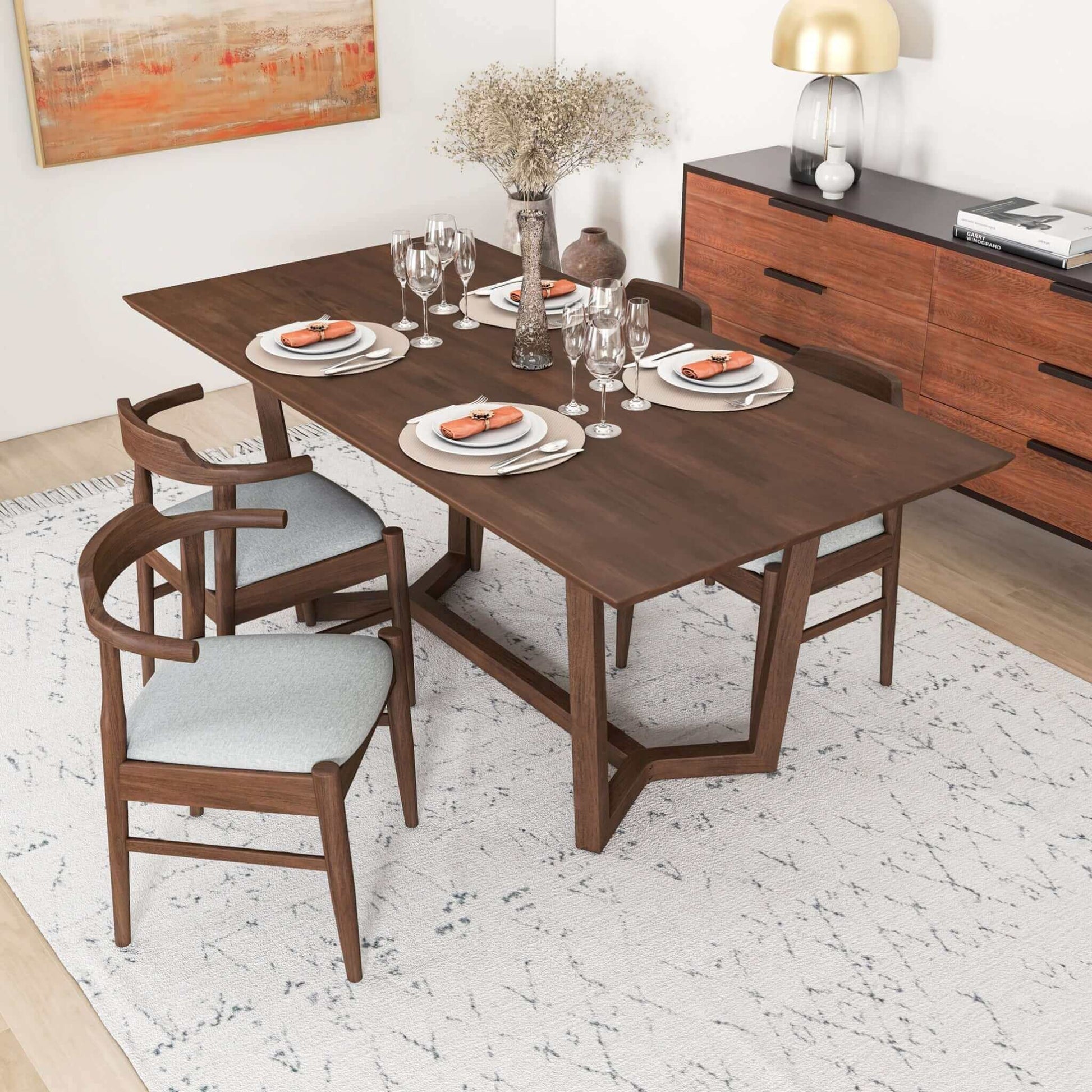 Modern wood dining table set with four chairs, tableware, and decor in a stylish home interior