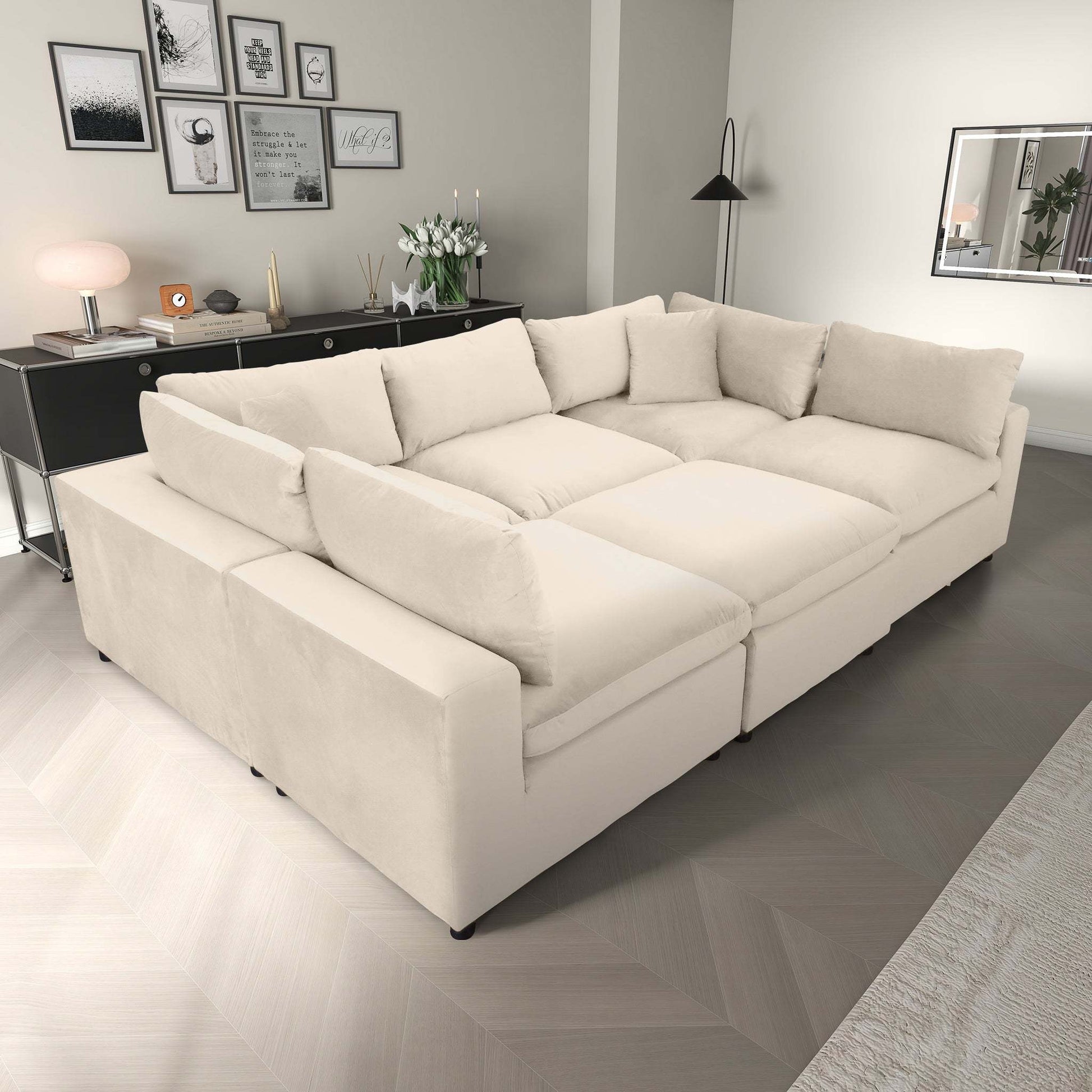 Modern living room with a large beige sectional sofa, decorative pillows, and stylish wall art